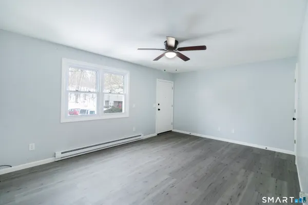 a view of empty room with wooden floor and fan