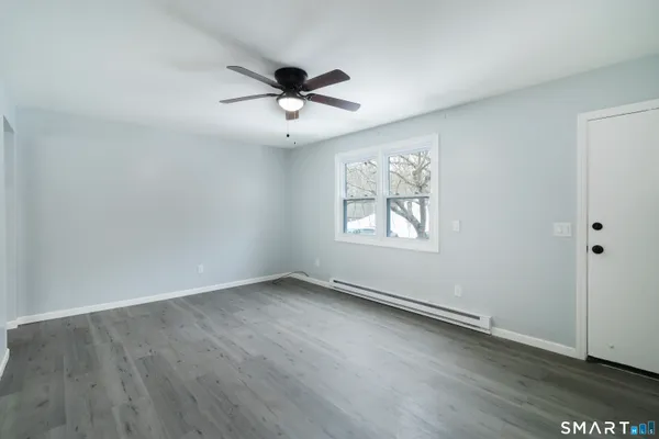 an empty room with wooden floor ceiling fan and windows