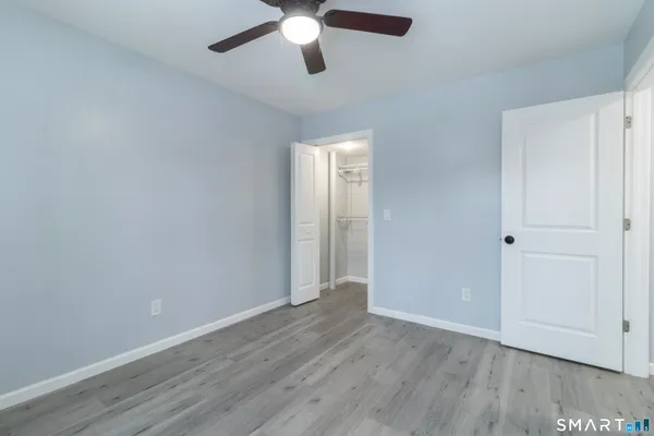an empty room with wooden floor chandelier fan and windows