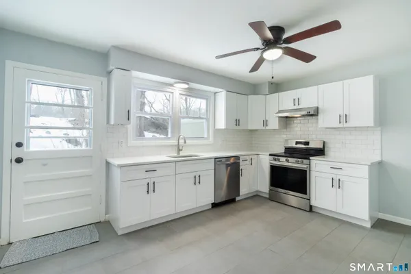 a kitchen with granite countertop white cabinets white stainless steel appliances and a window