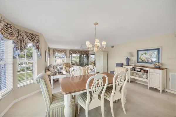 a view of a dining room with furniture a chandelier and large windows
