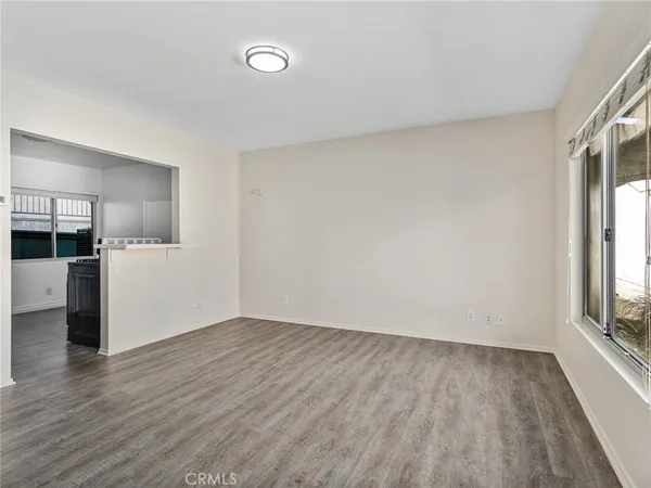a view of empty room with wooden floor and window