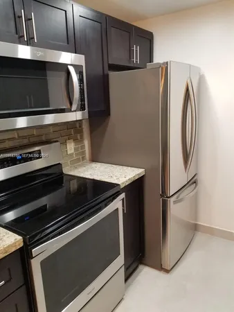 a kitchen with stainless steel appliances granite countertop a refrigerator and a sink