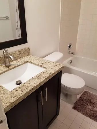 a bathroom with a granite countertop sink toilet and a mirror