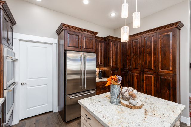 1132 Sunset Dunes Way Draper, UT 84020 - Photo 5 of 35 Kitchen featuring dark wood cabinetry with crown molding, stainless steel refrigerator, built-in stainless steel double ovens, a center island with light-toned countertop, and recessed and pendant lighting