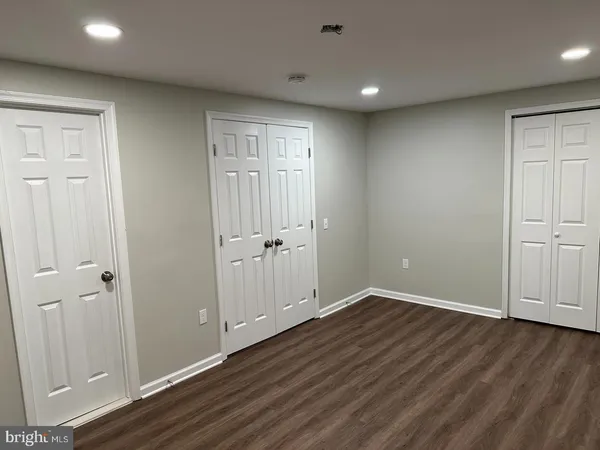 an empty room with wooden floor and closet area