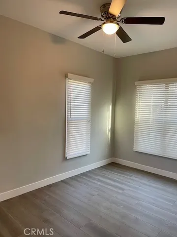an empty room with wooden floor fan and windows