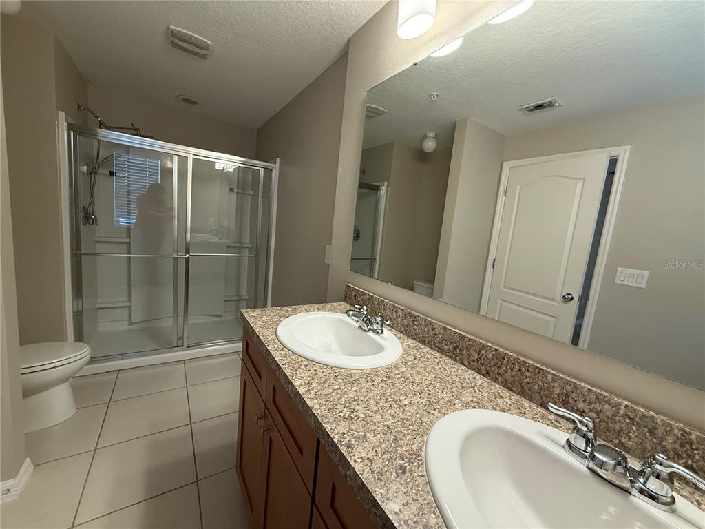 1623 Reflection Cove St. Cloud, FL 34771 - Photo 16 of 33 a bathroom with a granite countertop sink a mirror and a toilet