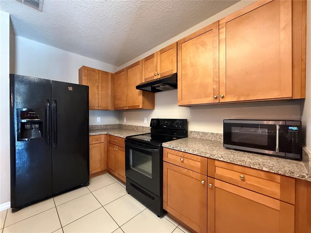 1623 Reflection Cove St. Cloud, FL 34771 - Photo 6 of 33 a kitchen with stainless steel appliances granite countertop a refrigerator stove and microwave