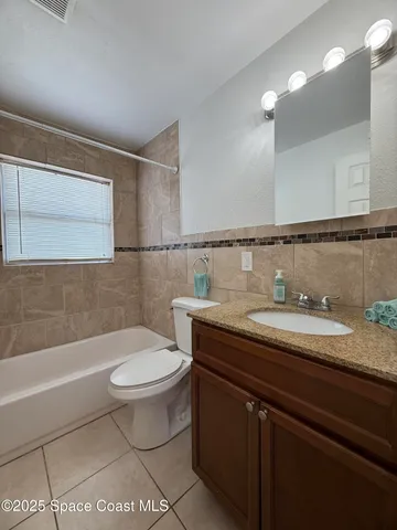 a bathroom with a granite countertop sink a toilet a mirror and bathtub
