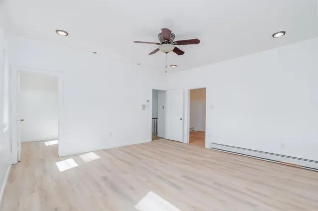 a view of empty room with wooden floor and ceiling fan