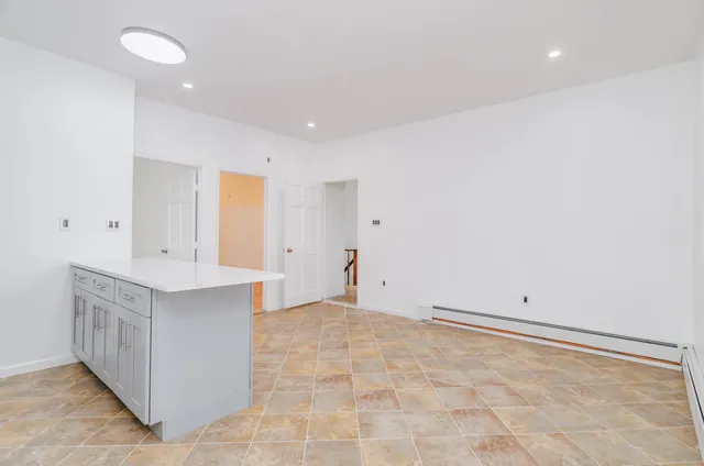 a view of an empty room with kitchen and a sink