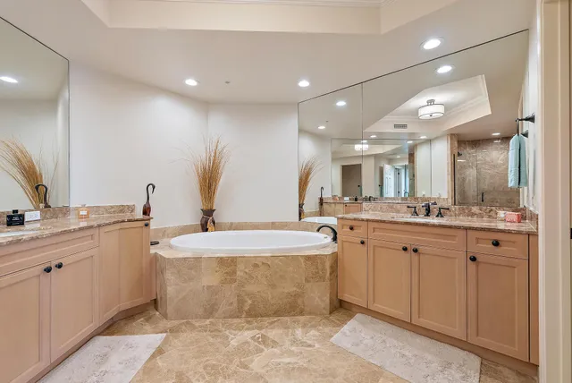 a spacious bathroom with a double vanity sink mirror and bathtub