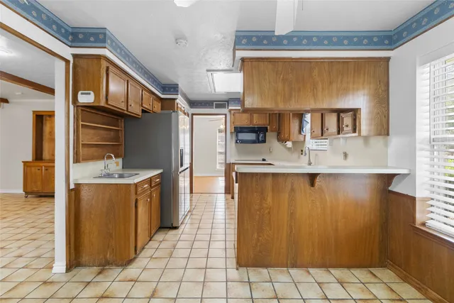 a view of kitchen with stainless steel appliances granite countertop a sink and a refrigerator