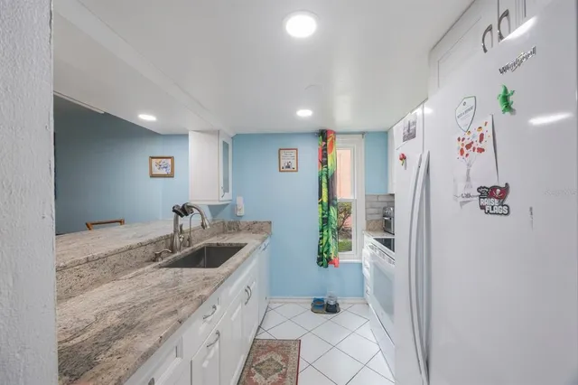 a kitchen with granite countertop a refrigerator and a sink