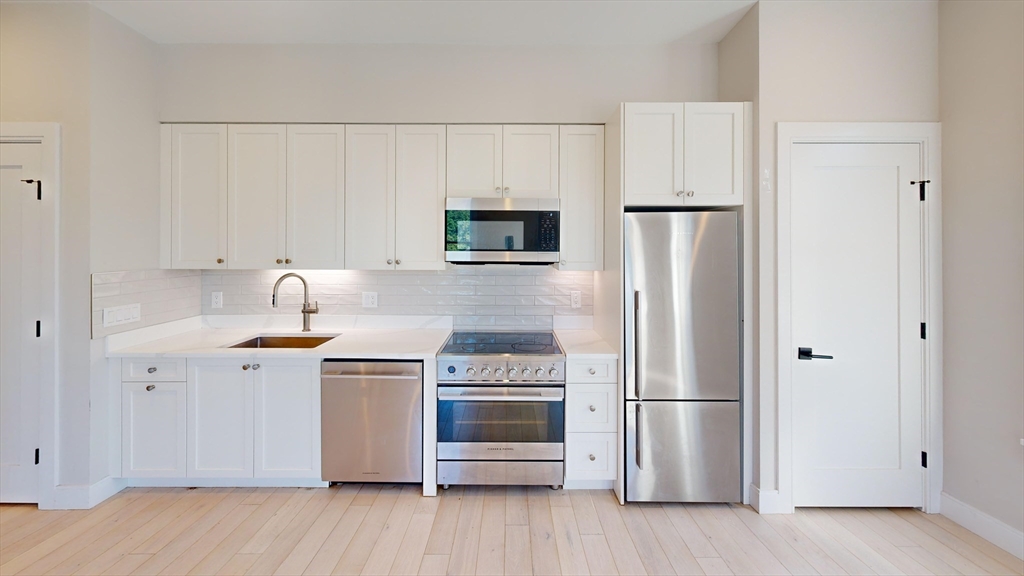197 Green Street, Unit 401 Boston, MA 02130 - Photo 1 of 5 a kitchen with a refrigerator stove and white cabinets