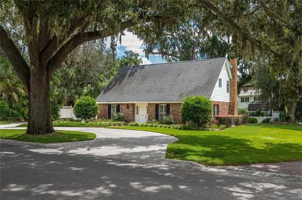 a view of a big house with a big yard and large trees