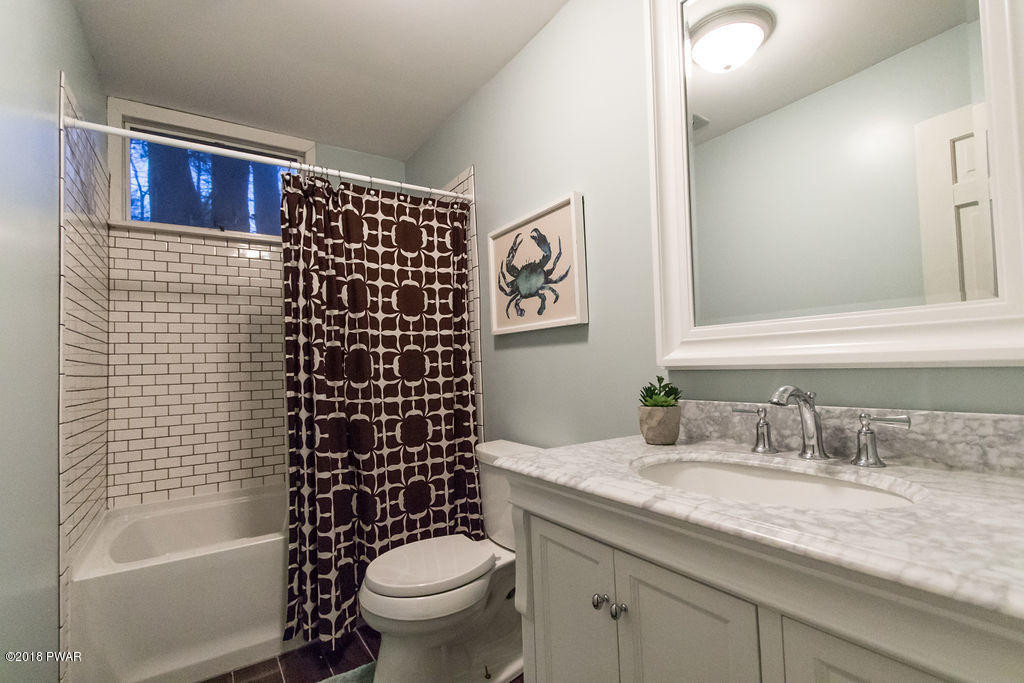 139 Raccoon Court Bushkill, PA 18324 - Photo 11 of 17 a bathroom with a granite countertop toilet a sink a mirror a shower a vanity and bathtub