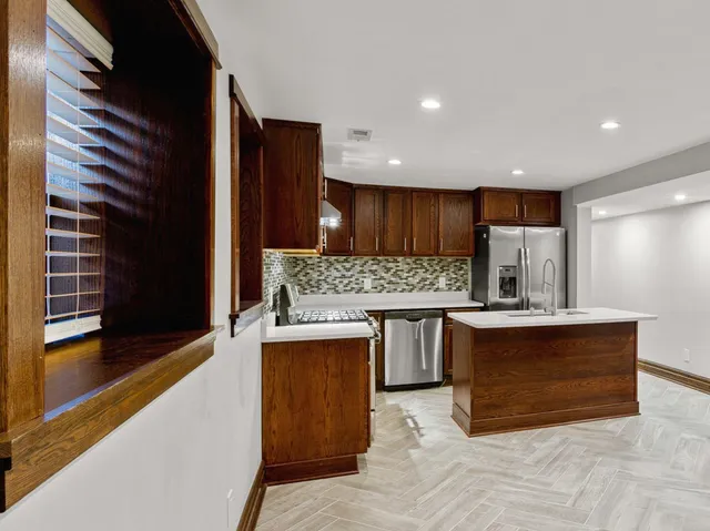 a kitchen with kitchen island a sink stainless steel appliances and cabinets