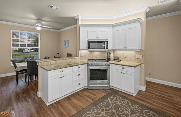 a kitchen with granite countertop a sink appliances cabinets and wooden floor