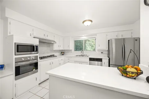 a kitchen with a sink dishwasher stove and white cabinets