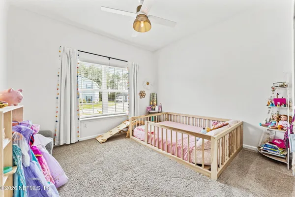 a bedroom with baby crib and a window