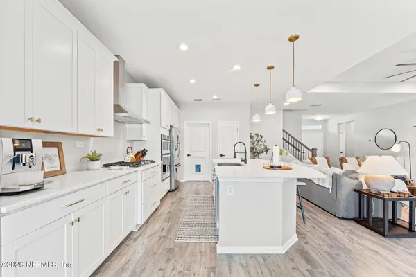 a large white kitchen with lots of counter space a sink appliances and cabinets