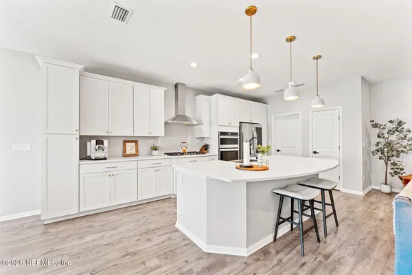 a kitchen with stainless steel appliances kitchen island granite countertop a table chairs and a refrigerator