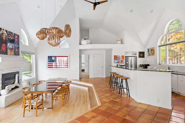 a living room with stainless steel appliances furniture a dining table and a bookshelf