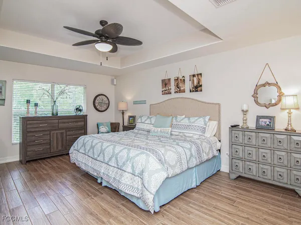 a bedroom with a bed a dresser and wooden floor