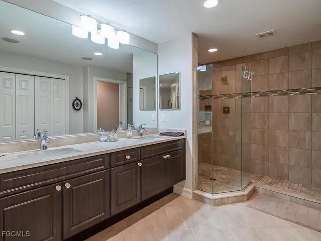 a bathroom with a double vanity sink mirror and shower