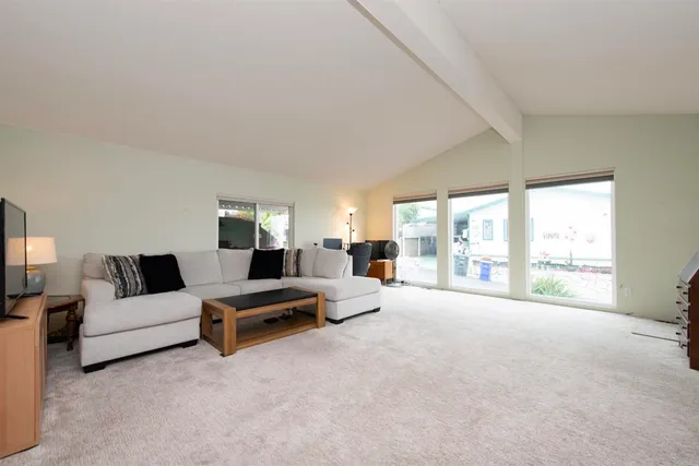 a living room with furniture white walls and a large window