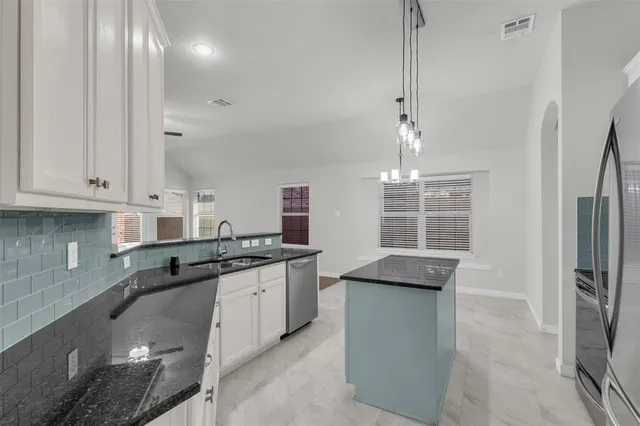 a kitchen with granite countertop a sink stainless steel appliances and cabinets