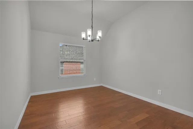 en empty room with wooden floor chandelier and window