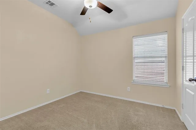 an empty room with a window and a ceiling fan