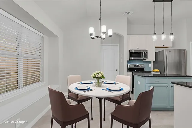 a kitchen with stainless steel appliances a dining table chairs and a microwave