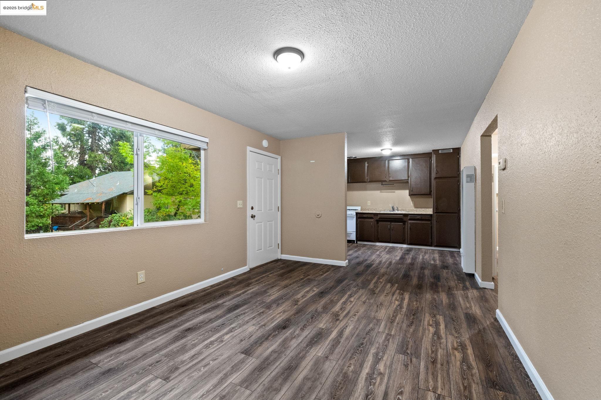 17943 Plateau Road Sonora, CA 95370 - Photo 5 of 11 Unfurnished living room featuring a textured wall, dark wood-style floors, a textured ceiling, and a heating unit