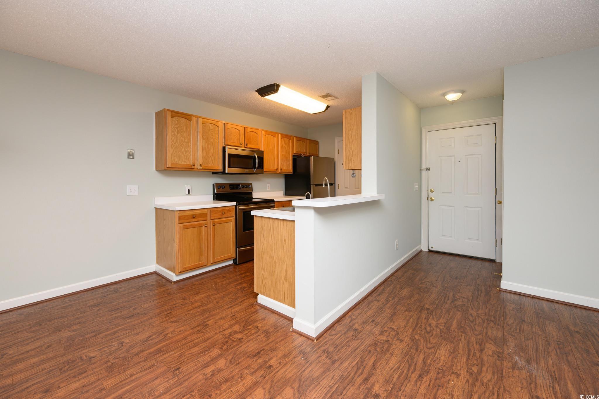4283 Santolina Way, Unit D Murrells Inlet, SC 29576 - Photo 2 of 31 Kitchen featuring light countertops, appliances with stainless steel finishes, dark wood finished floors, and a peninsula