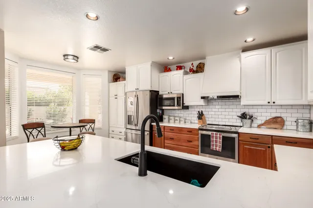 a kitchen with stainless steel appliances a stove a sink a refrigerator a center island and furniture