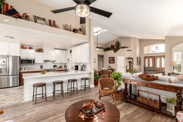 a living room with stainless steel appliances kitchen island granite countertop furniture a rug kitchen view and a chandelier