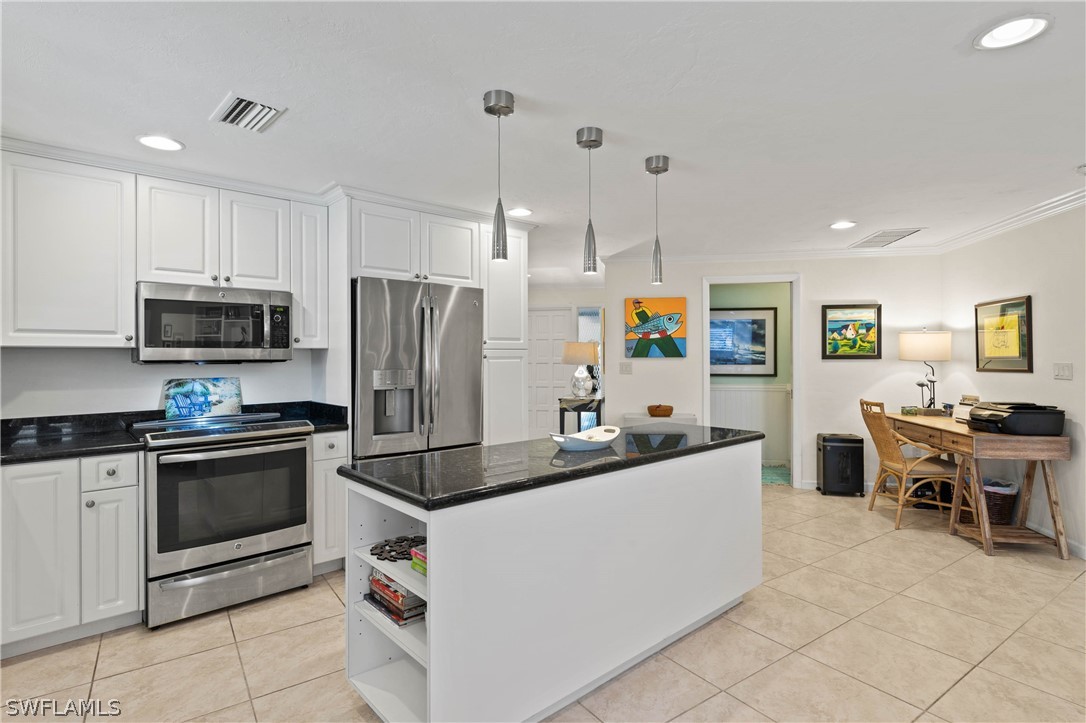 975 Sand Castle Road Sanibel, FL 33957 - Photo 10 of 24 a kitchen with stainless steel appliances a stove a sink a microwave a refrigerator a dining table and chairs with wooden floor