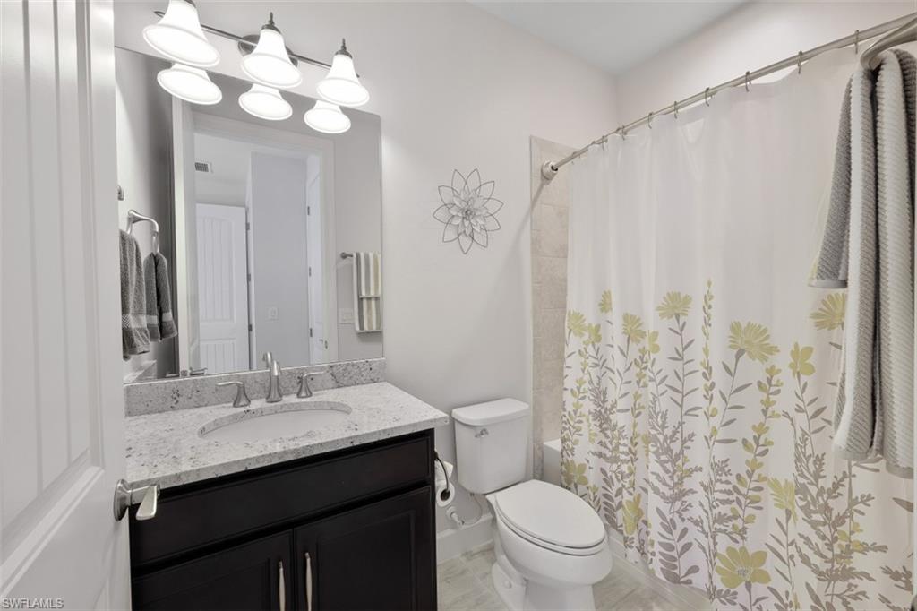 9431 Greyhawk Trail Naples, FL 34120 - Photo 22 of 50 a bathroom with a granite countertop sink a toilet and a mirror