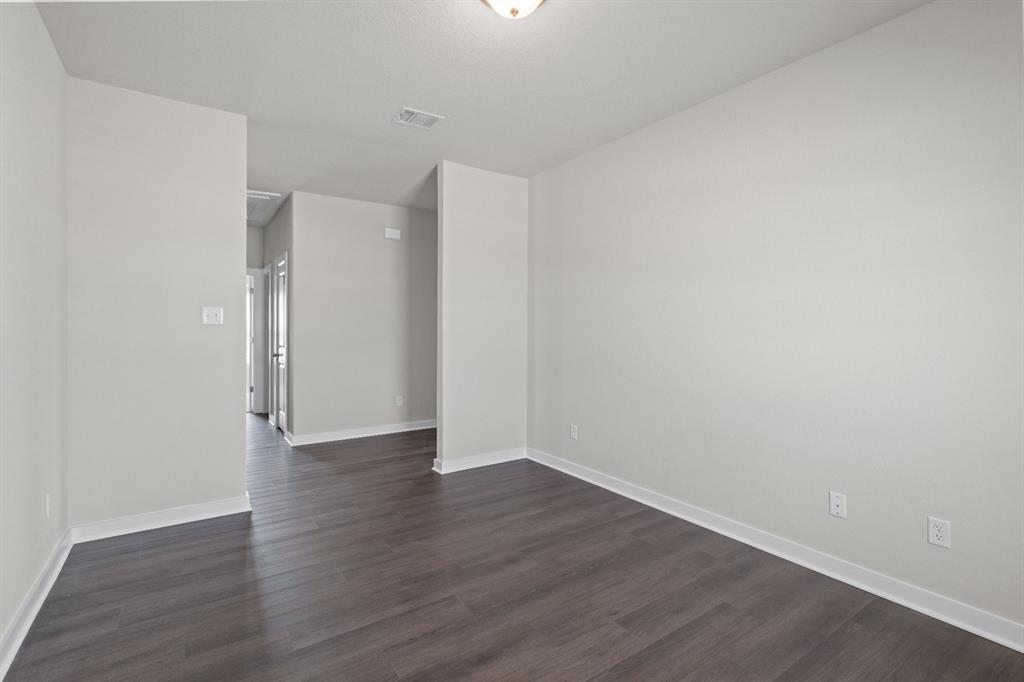 177 Sleep Hollow Jarrell, TX 76537 - Photo 20 of 24 Spacious interior room featuring dark wood-finish flooring, light neutral-toned walls, white baseboards, and a semi-flush ceiling light fixture