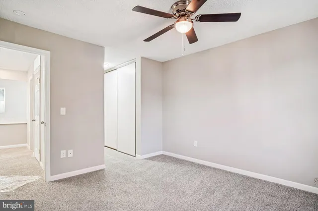 an empty room with a window and a fan
