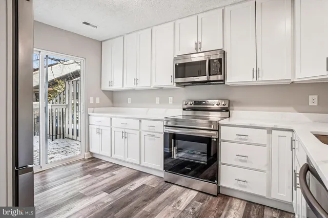 a kitchen with stainless steel appliances granite countertop a stove a microwave and a white cabinets