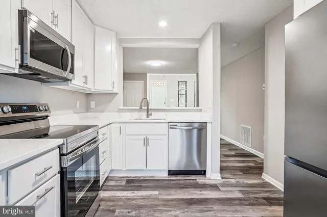 a kitchen with stainless steel appliances granite countertop a sink a stove a microwave and wooden cabinets