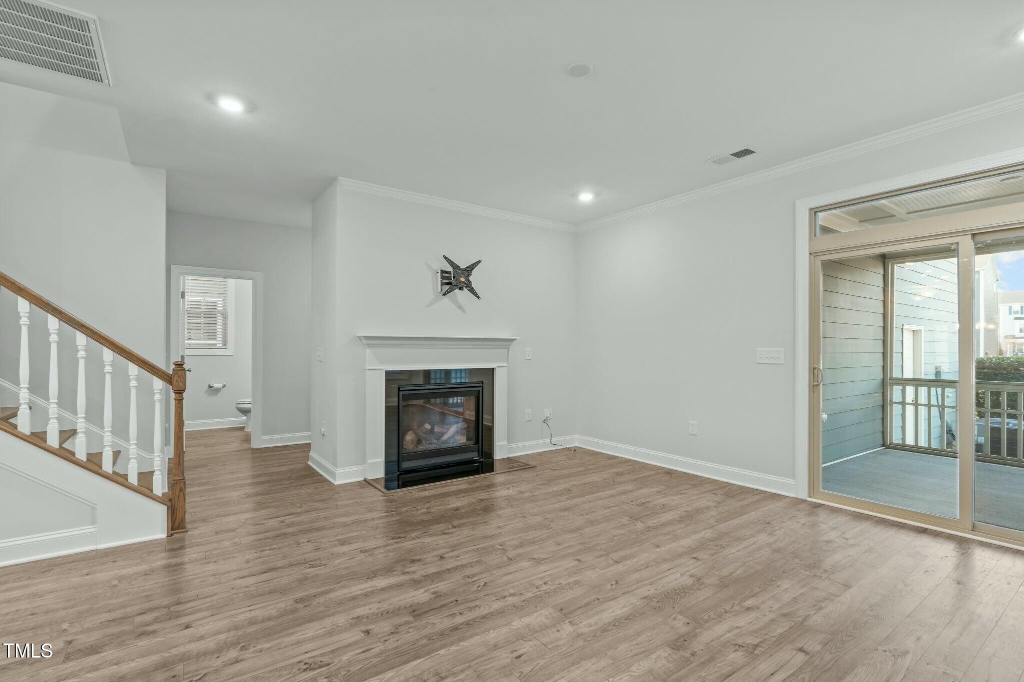 6417 Truxton Lane Raleigh, NC 27616 - Photo 17 of 47 an empty room with wooden floor fireplace and windows