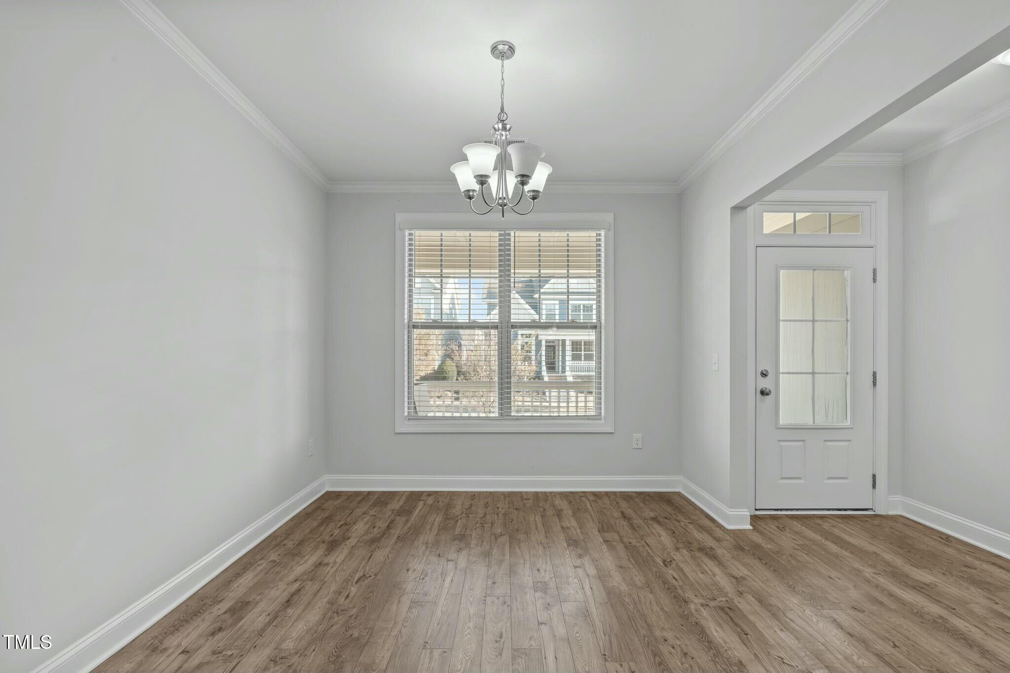 6417 Truxton Lane Raleigh, NC 27616 - Photo 8 of 47 an empty room with wooden floor chandelier and windows