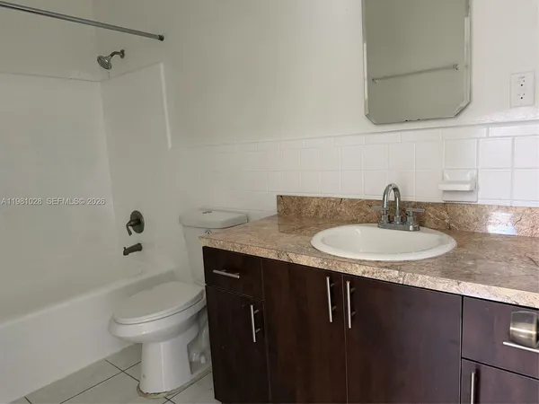 a bathroom with a granite countertop sink a toilet and shower