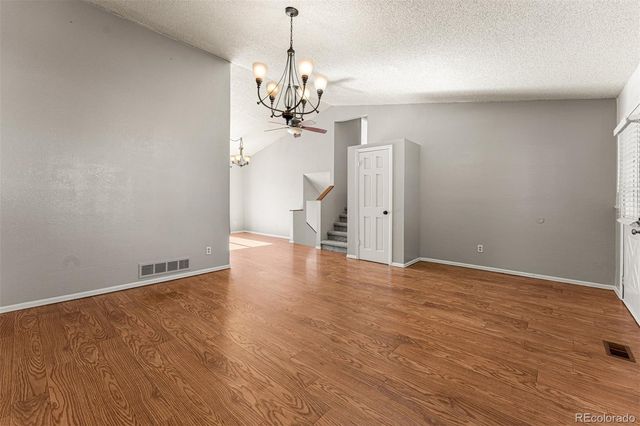 a view of an empty room with wooden floor and chandelier